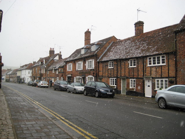 Timber-framed cottages line Whielden Street in Amersham Old Town as snow falls over parked cars.