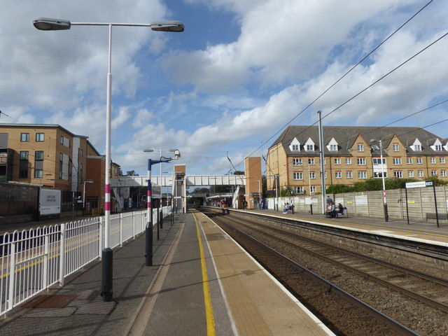 Borehamwood railway station in Hertfordshire, looking north along the platform with the footbridge and surrounding buildings visible.