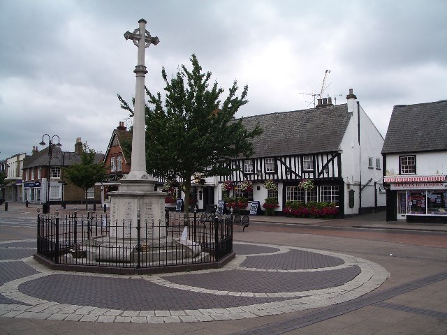 The war memorial in Hoddesdon town centre, Hertfordshire, with the timber-framed high street buildings behind it.