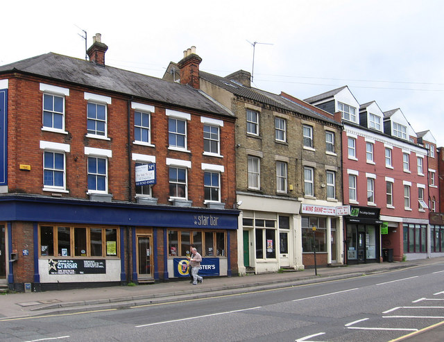 A row of red-brick and Victorian shopfronts, including the Star Bar, along a street in Wellingborough town centre.